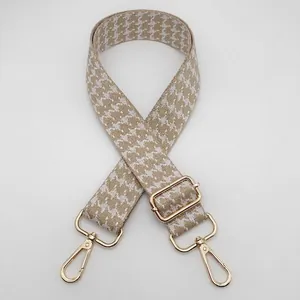 Close-up of khaki houndstooth wide bag strap with gold metal hooks and jacquard texture