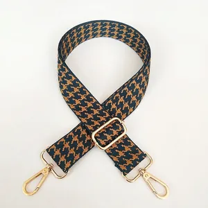 Detail of adjustable wide shoulder strap with navy houndstooth pattern and gold hardware