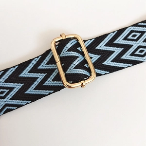 Détail de la bandoulière tissée avec motif zigzag noir et bleu et boucle dorée