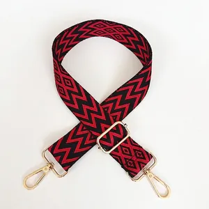 Détail de la bandoulière en jacquard rouge et noir avec crochets en métal doré réglables