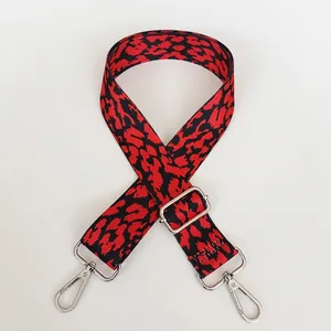 Detail of red and black leopard print adjustable wide bag strap with silver metal hooks