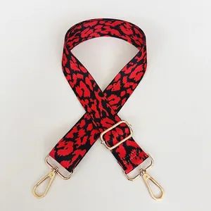 Detail of red and black leopard print wide bag strap with gold metal hardware and hooks