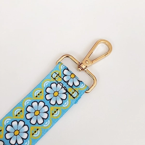 Close-up of light blue floral strap with white daisy pattern and golden metal hook