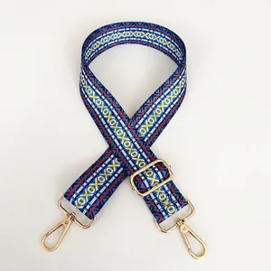 Close-up of ethnic geometric pattern woven strap with gold metal hooks and slider