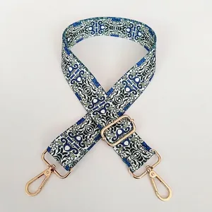 Detail of adjustable folk style woven bag strap with geometric patterns and gold metal hooks
