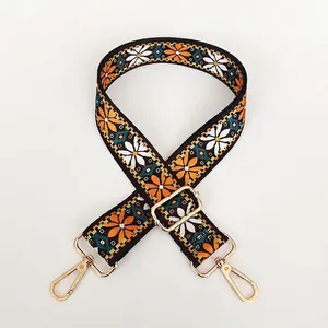 Close-up of ethnic style daisy embroidered handbag strap with gold metal hooks and buckle