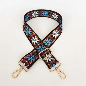 Detail of folk-style bag strap with blue sunflower embroidery and golden lobster hooks