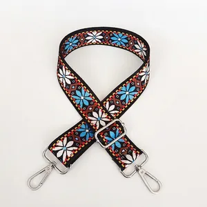 Detail view of ethnic boho wide bag strap with blue floral patterns and silver hardware