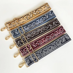 Detail view of five adjustable canvas bag straps with paisley patterns and gold metal clips