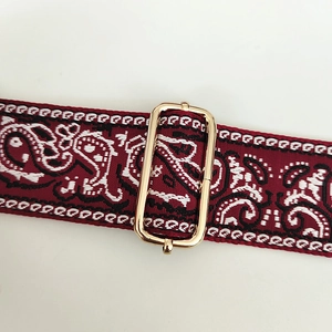 Macro shot of paisley woven shoulder strap with polished gold adjustable metal buckle