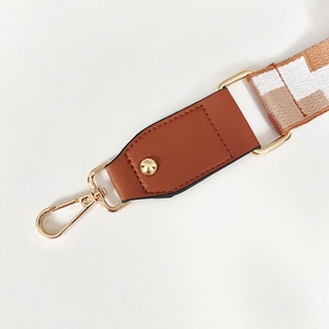 Détail de la bandoulière brodée réglable avec boucle dorée et connecteur en cuir