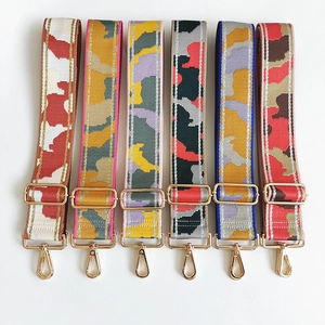 Close-up of wide nylon bag straps in multi-color camouflage patterns with gold metal hooks