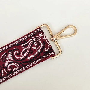Detail of vintage jacquard pattern on wide canvas bag strap with golden metal clasp