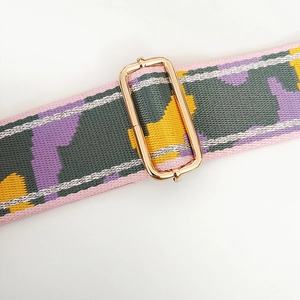 Detailed close-up of colorful camouflage nylon bag strap with gold metal buckle