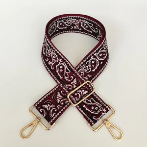 Close-up of a 5cm wide red canvas strap with white paisley patterns and gold metal hooks