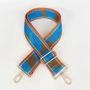 Detail of blue camo nylon shoulder strap with gold metal hooks and textured jacquard weave
