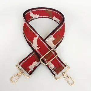 Detail view of wide nylon bag strap with red geometric pattern and gold metal hardware