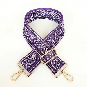 Detail of purple paisley canvas bag strap with golden metal swivel hooks and adjuster