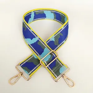 Detail of blue and green camo nylon bag strap with gold metal hooks and yellow borders