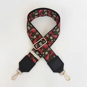 Détail de la broderie florale sur sangle verte avec cuir noir et mousquetons dorés