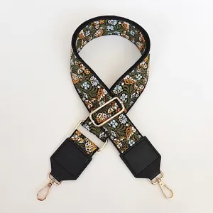 Détail de la broderie florale sur bandoulière large verte avec cuir noir et crochets dorés