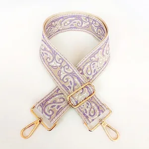 Detail of purple paisley 5cm wide canvas bag strap with golden metal swivel hooks