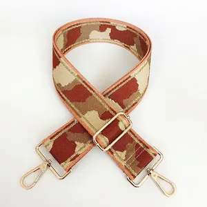 Detail of adjustable camouflage nylon bag strap with gold threads and metal hooks