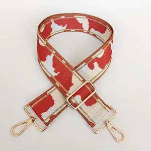 Close-up of tricolor geometric nylon bag strap with gold metal hooks and adjusters