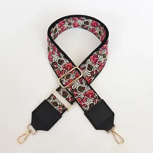 Détail de la bandoulière brodée florale rose avec bouts en cuir noir et crochets dorés