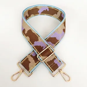 Detail of adjustable nylon bag strap with purple geometric patterns and gold hardware