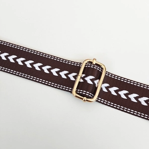 Close-up of adjustable chevron jacquard bag strap with polished gold metal buckle
