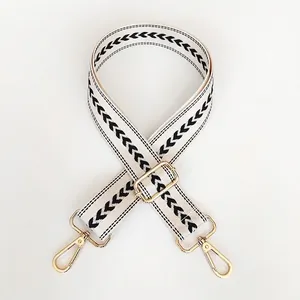Detail view of off-white jacquard wide shoulder strap with black chevron patterns and gold hooks