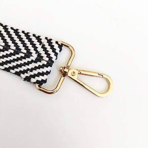 Close-up of black and white herringbone woven strap with polished gold metal buckle