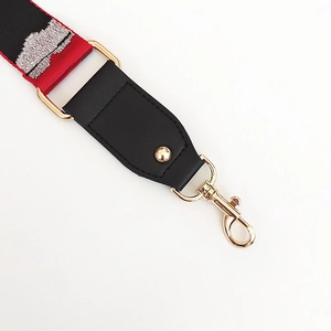 Close-up of red and black geometric embroidery strap with gold lobster clasps and leather ends