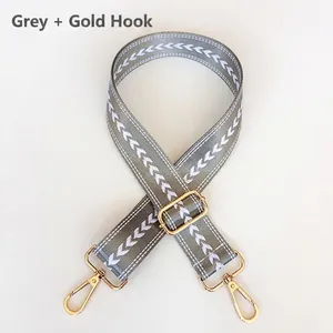 Close-up of gray woven jacquard shoulder strap with white patterns and gold hardware