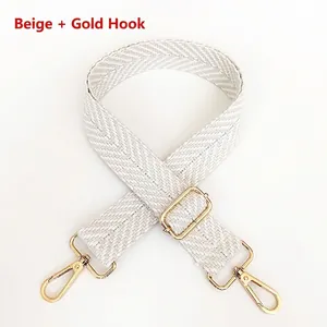 Close-up of adjustable beige cotton strap with gold metal lobster clasps and buckle