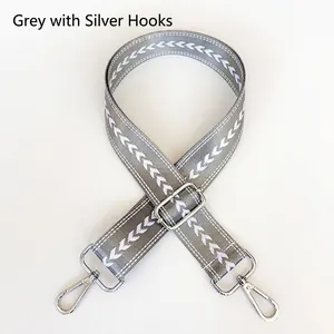 Detail view of grey nylon shoulder strap with white patterns and silver metal hooks
