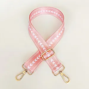 Detail of adjustable pink nylon bag strap with white chevron patterns and gold hooks