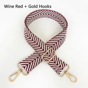 Detail of wine red and white herringbone woven wide bag strap with gold metal hooks