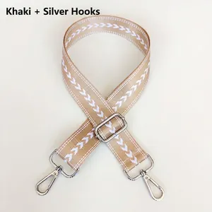 Detail of khaki nylon wide strap with white V-pattern and silver metal hooks
