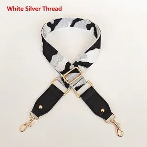 Detail of wide white and silver geometric strap with gold-tone hardware and black leather