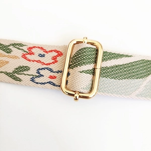 Detail of embroidered floral canvas strap with golden metal adjustable buckle for handbags