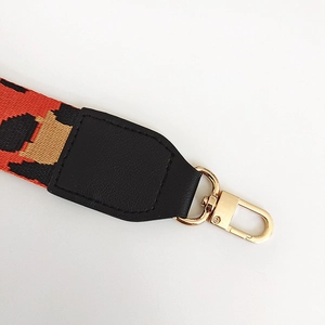 Close-up of leopard print phone strap with orange weaving and golden metal hook