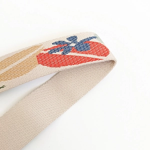 Close-up of embroidered wide canvas bag strap with colorful floral patterns and woven texture