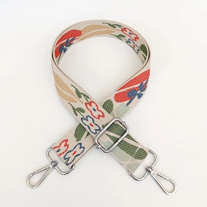 Detail of floral embroidered canvas strap with silver lobster claws and adjustable buckle