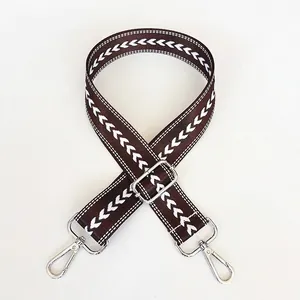 Close-up of coffee brown jacquard bag strap with white V-pattern and silver metal clasps