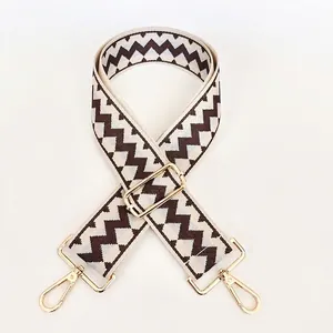 Close-up of ethnic style wide woven shoulder strap with gold metal hooks and wave pattern