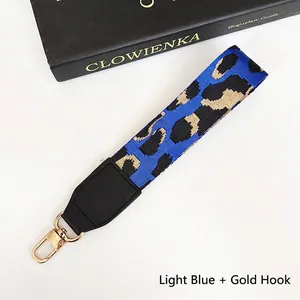 Close-up of light blue leopard print phone strap with black faux leather and gold metal clip