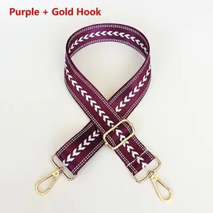 Detail of adjustable purple woven nylon strap with white geometric patterns and gold hooks