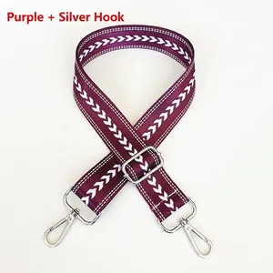 Close-up of purple nylon jacquard bag strap with silver metal hooks and white arrow pattern